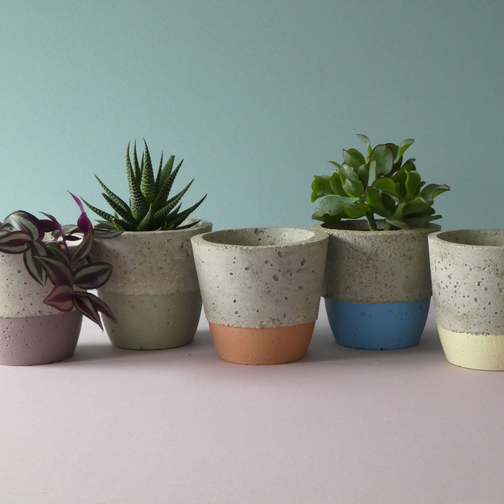A handcrafted and lightweight small concrete pot for every day use. It is handmade and has a painted bottom stripe. A Scandinavian decorative vessel with a minimalist look.