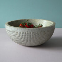 concrete textured bowl with green colour inside and fruit