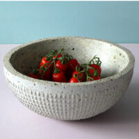 concrete textured bowl with green colour inside and tomatoes