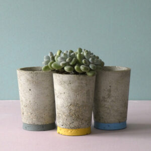 A handcrafted and lightweight small concrete pot for every day use. It is handmade and has a painted bottom stripe. A scandinavian decorative vessel with a minimalist look.